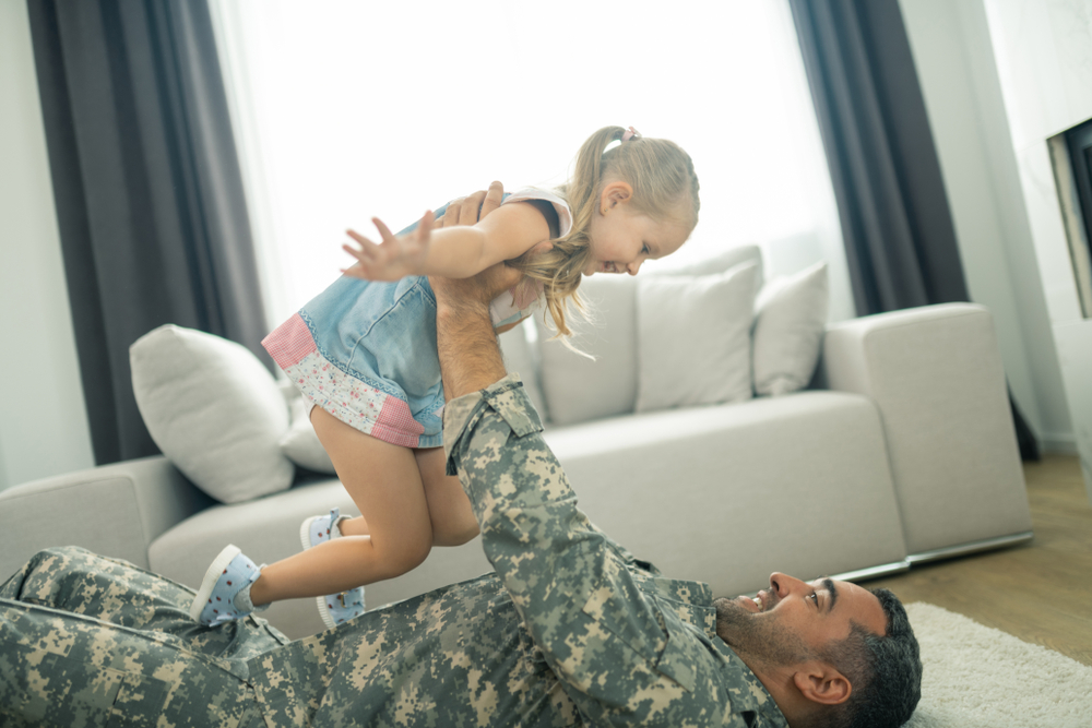 Lifting,Daughter.,Military,Man,Smiling,While,Lying,On,The,Floor